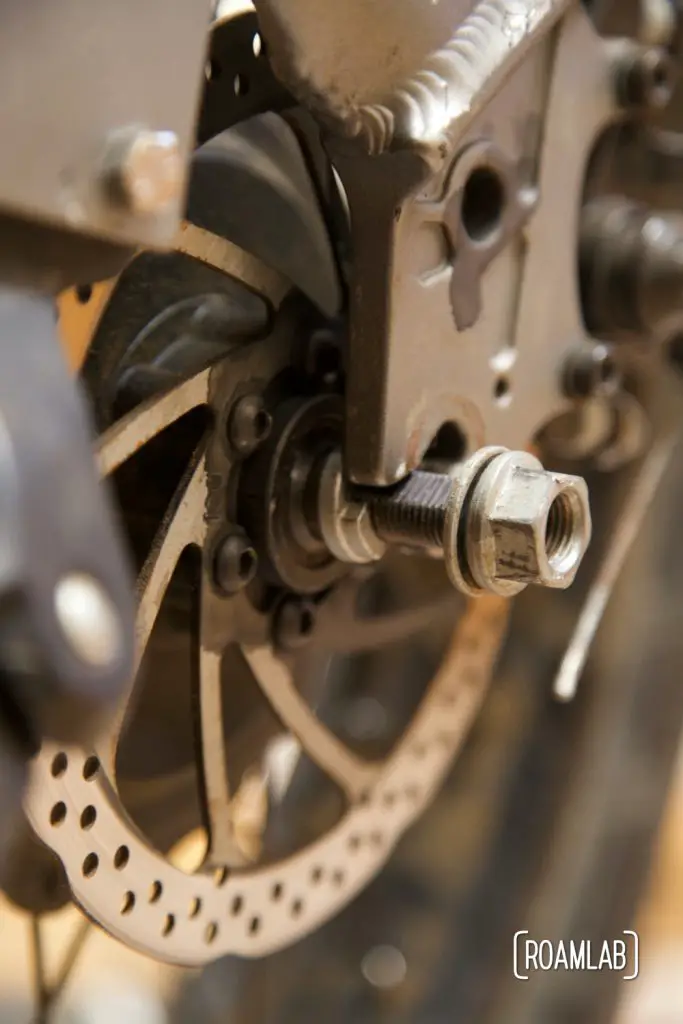 Close up view of partially seated rear axle with torque washer on the left and axel washer and nut on the right.