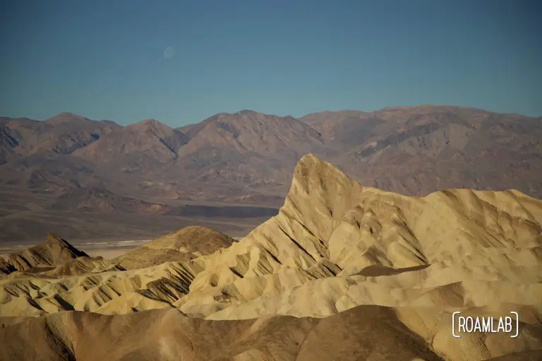 Towering golden rock formation of Zabriskie Point with the Panamint Range in the background.