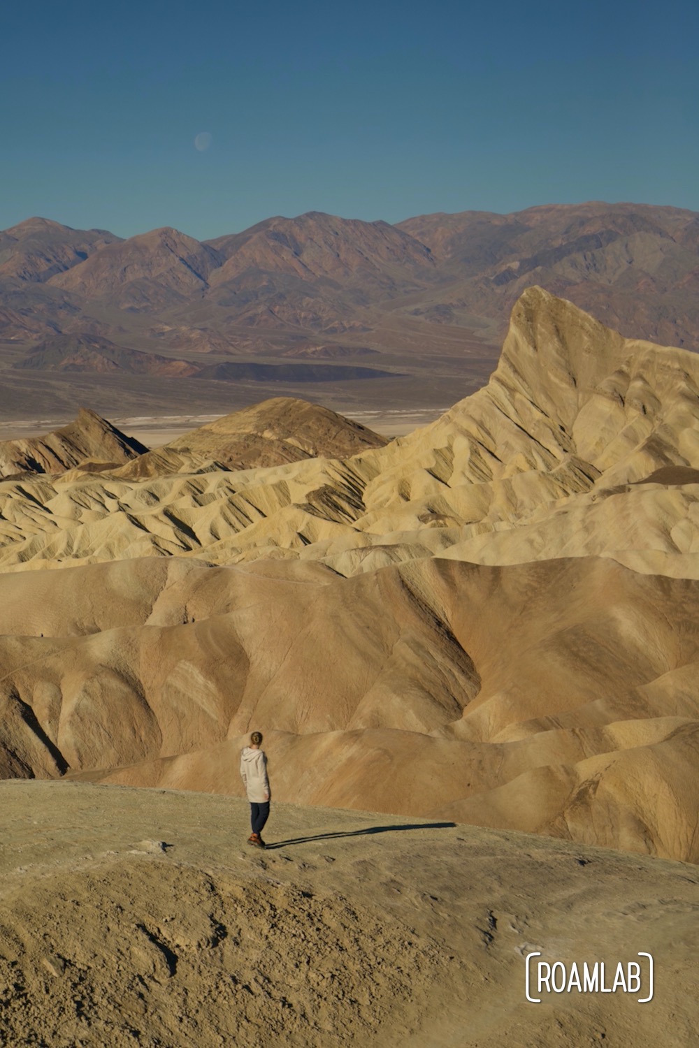 Towering golden rock formation of Zabriskie Point with the Panamint Range in the background.
