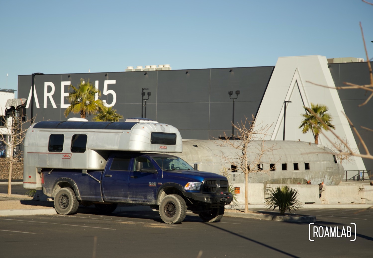 1970 Avion C11 truck camper parked in front of an airplane and Area 15: home of Omega Mart, Meow Wolf's Las Vegas location.