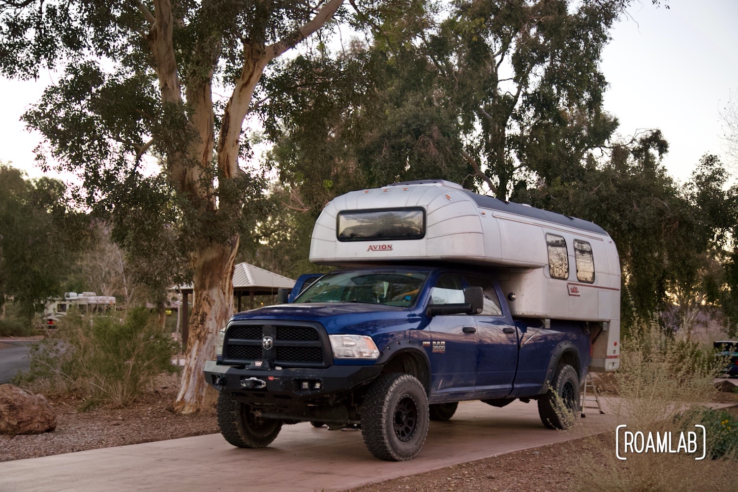 Parked in the shade of a tree on a cement pad, a 1970 Avion C11 truck camper is settled in Boulder Beach Campground, Lake Mead National Recreation Area, Nevada