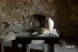 Pitcher, dishes, and cutlery on an old wooden table in an aging brick building in Shakespeare Ghost Town, New Mexico.