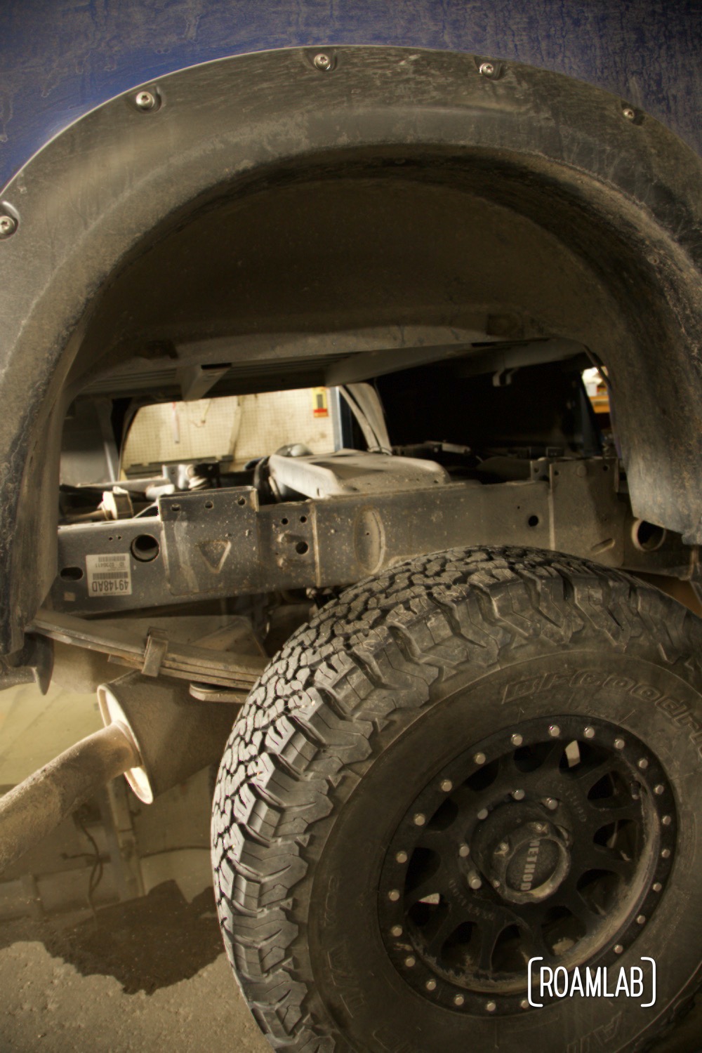 Truck bed fender suspended above truck frame and tires.