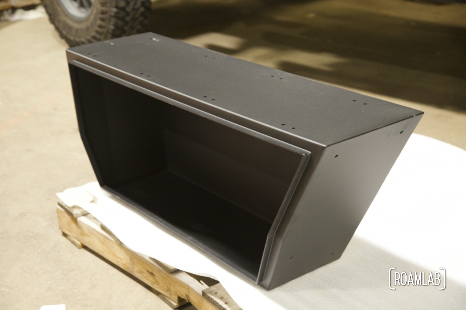 Black powder-coated lower truck bed box sitting on a wood pallet.