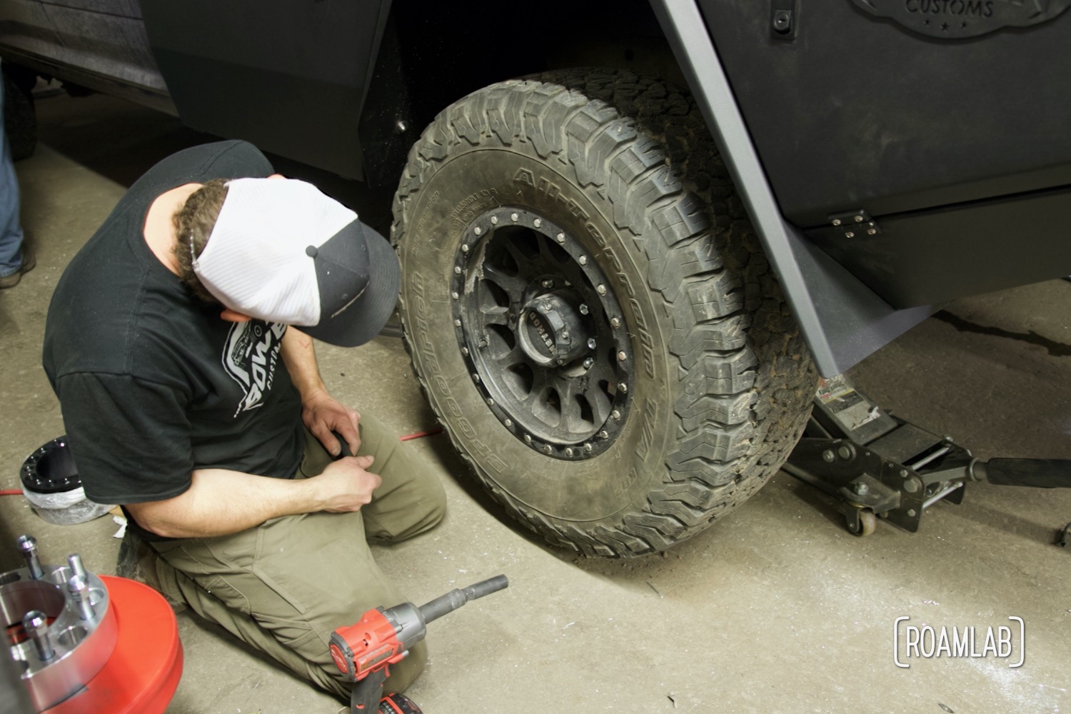Man inspecting a Method Racewheels and BF Goodrich KO2 tire remounted with space now sits nicely within the fender.