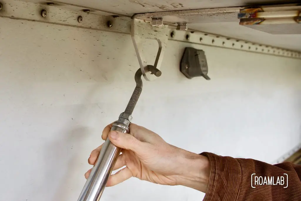 Hand hooking a turnbuckle into a custom truck camper mount point.