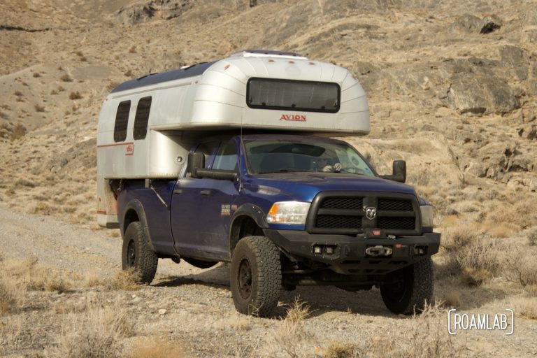 1970 Avion C11 truck camper on a blue truck driving along a dirt road on the Driving along the Silver Island Mountains Backcountry Byway outside Wendover, Utah.