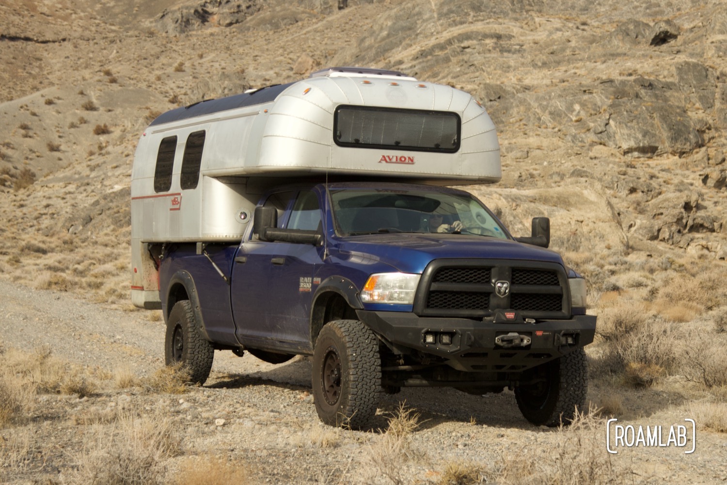 1970 Avion C11 truck camper on a blue truck driving along a dirt road on the Driving along the Silver Island Mountains Backcountry Byway outside Wendover, Utah.