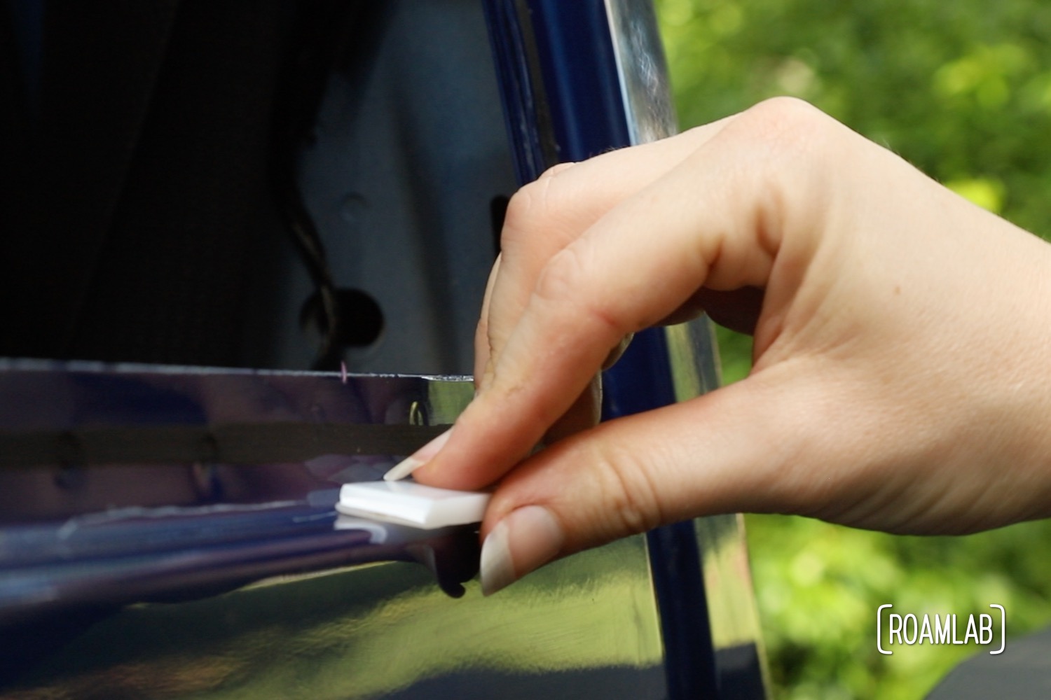 Hand holding a small spacer to the blue frame of a truck bed.