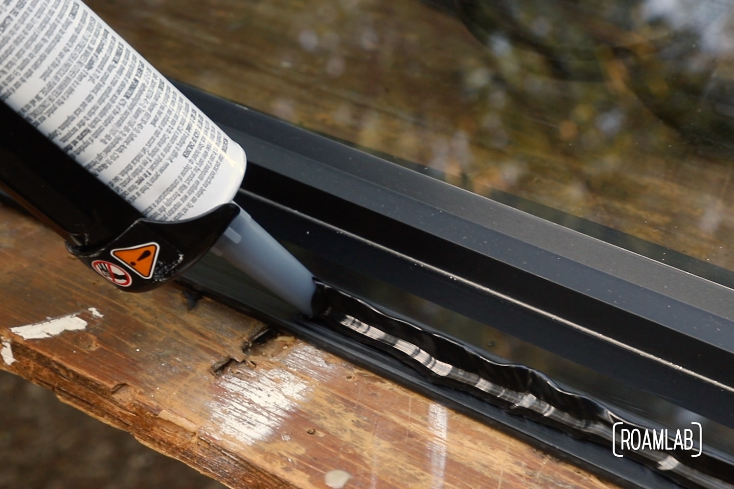 Close up view of an application gun laying down a peaked bead of urethane along the edge of a window.