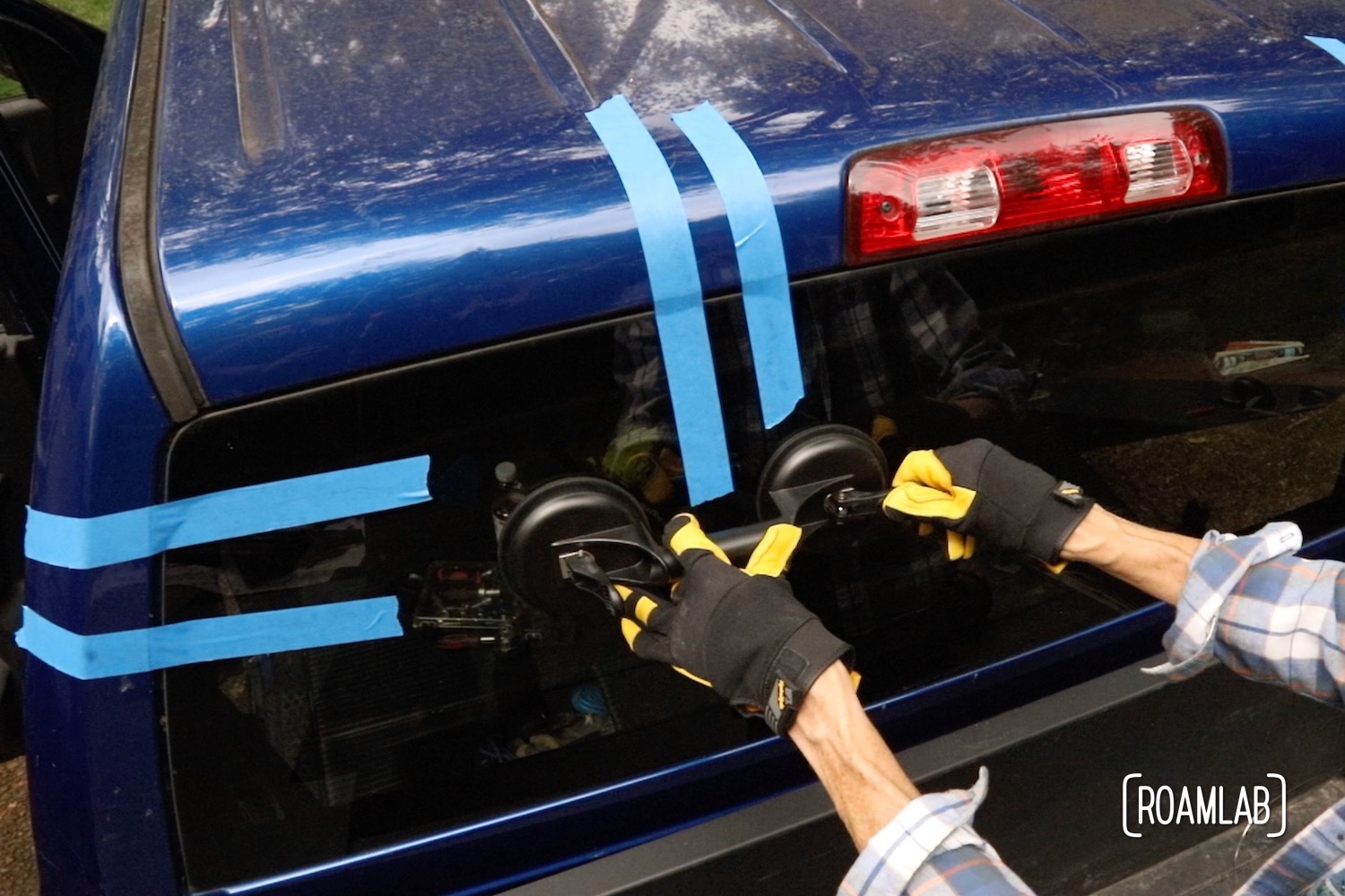 Gloved hand attaching a suction cup handle to a rear windshield.