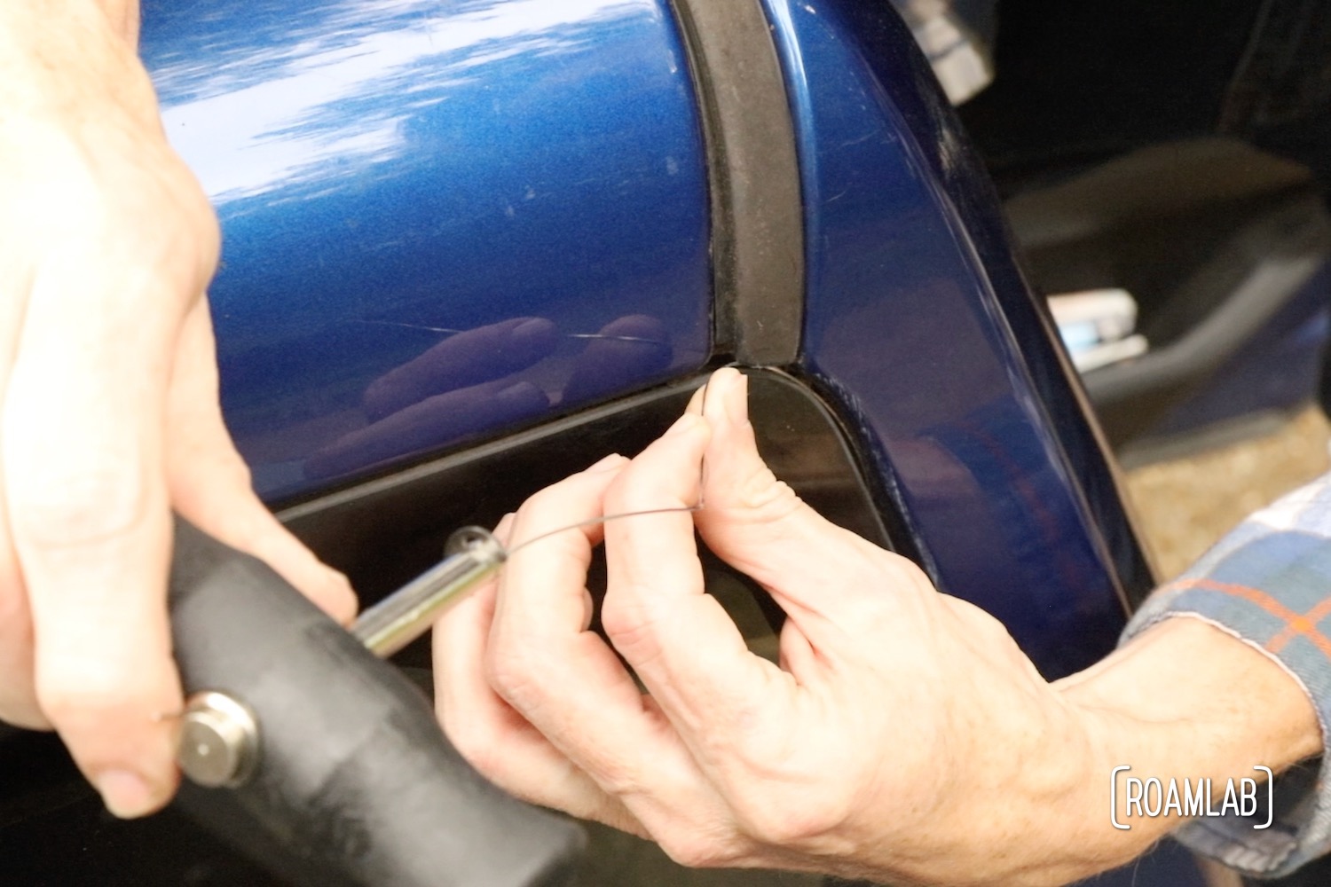 Hands wrapping cutting wire around the corner of a rear windshield.