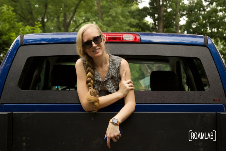 Woman leaning out an open rear truck window.