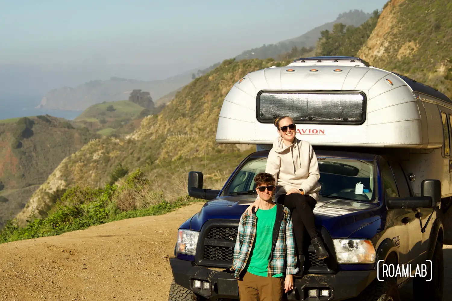 Lexi & Chris in front of their 1970 Avion C11 truck camper parked on the coast of Big Sur, California.