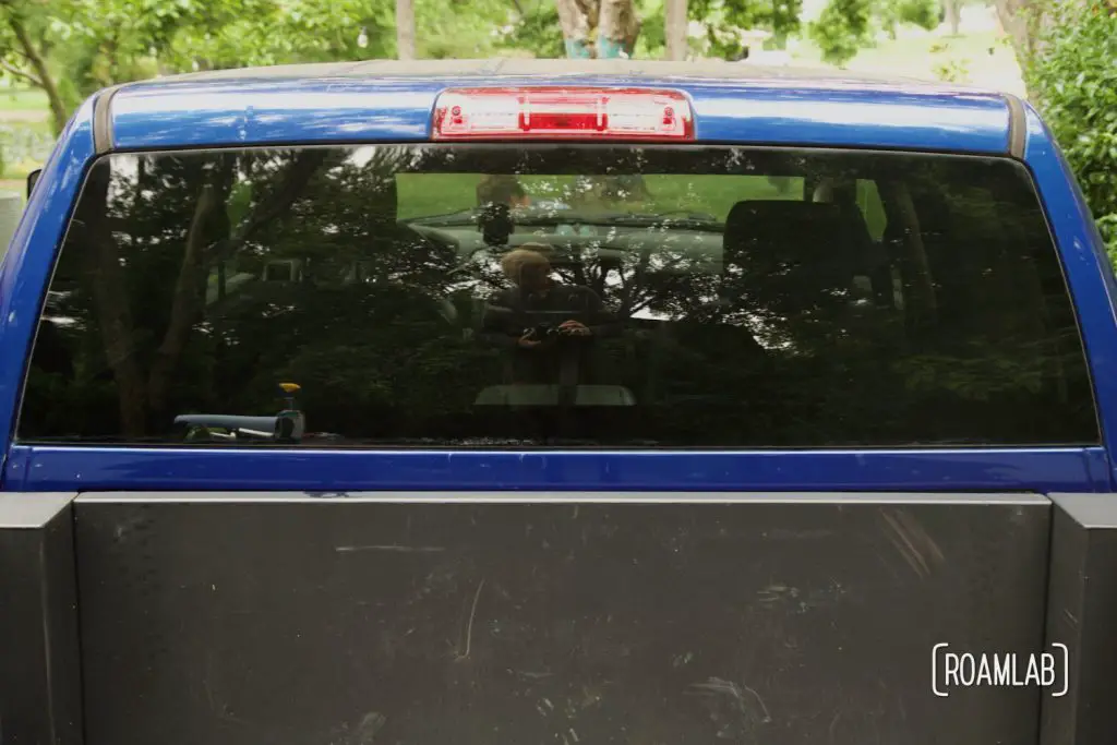 View of a blue trucks rear windshield as seen from the truck bed.