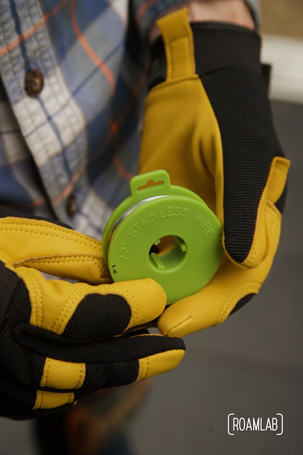 Gloved hands holding a spool of cutting wire.