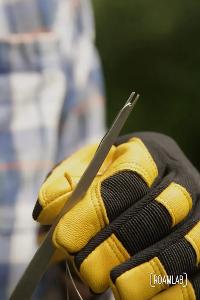 Gloved hands winding a cutting wire around the fire feeder.