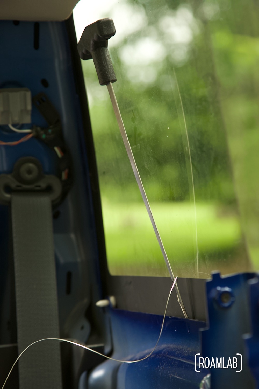 Wire feeder inserted into urethane between interior window and metal lip, feeding cutting wire to the outside.
