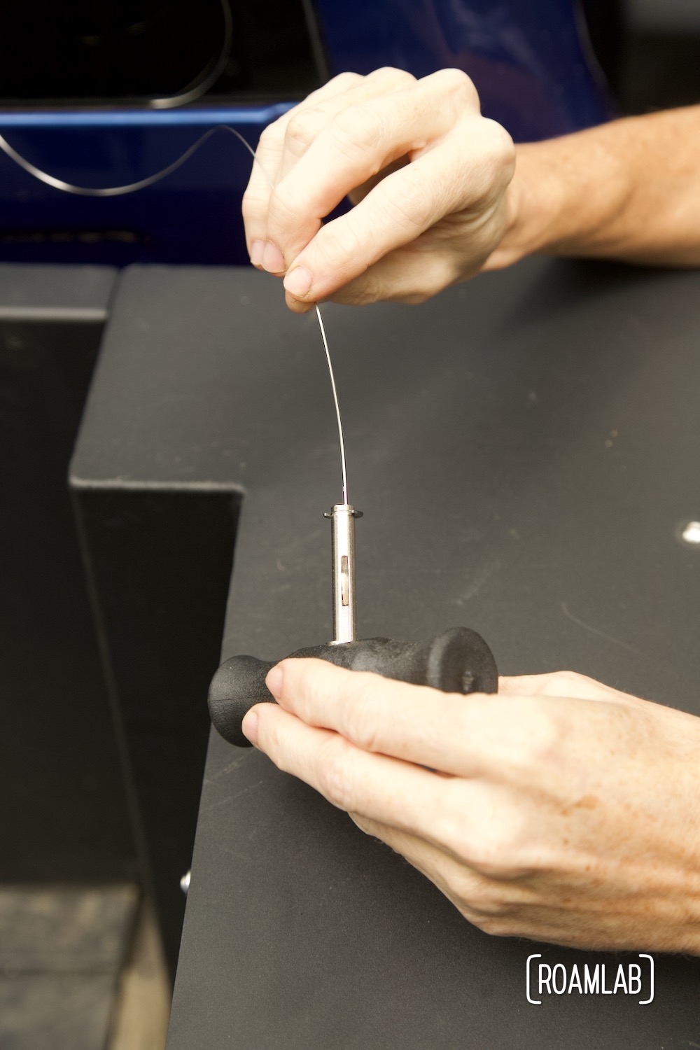 Hand threading cutting wire through the gripping handle shaft.