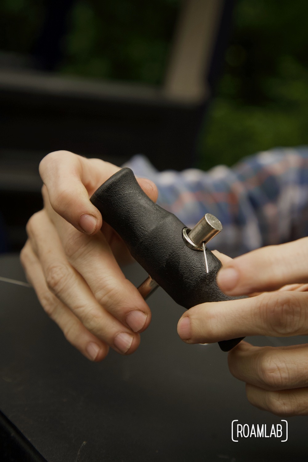 Hands holding a gripping handle with cutting wire secured in place.