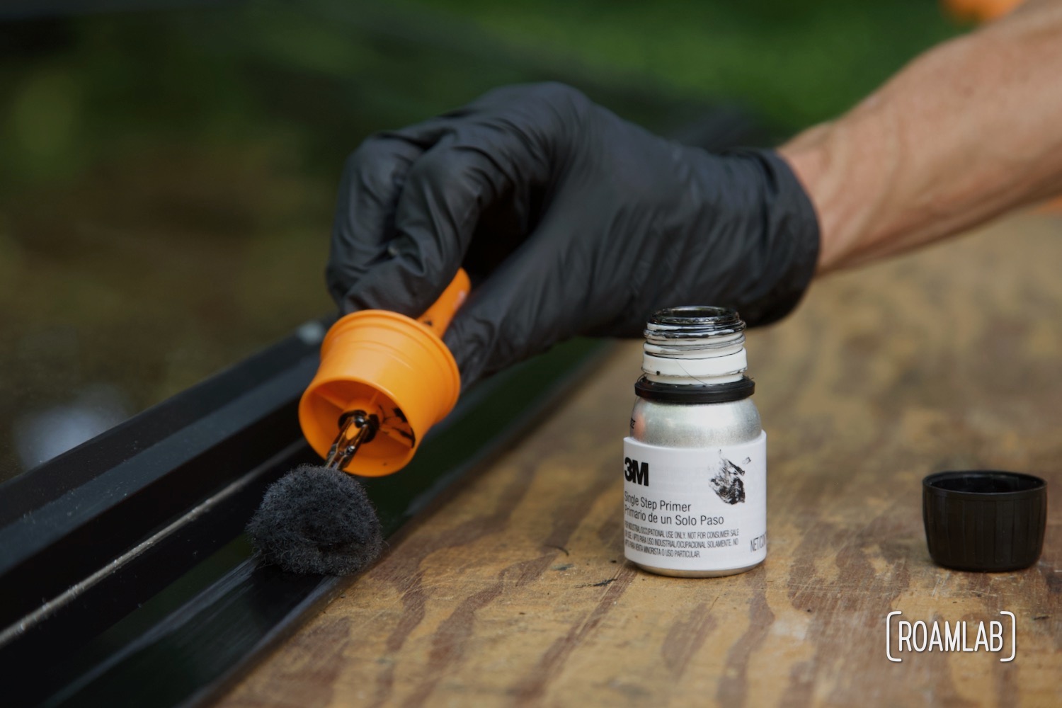 Gloved hand applying primer to the edge of a window