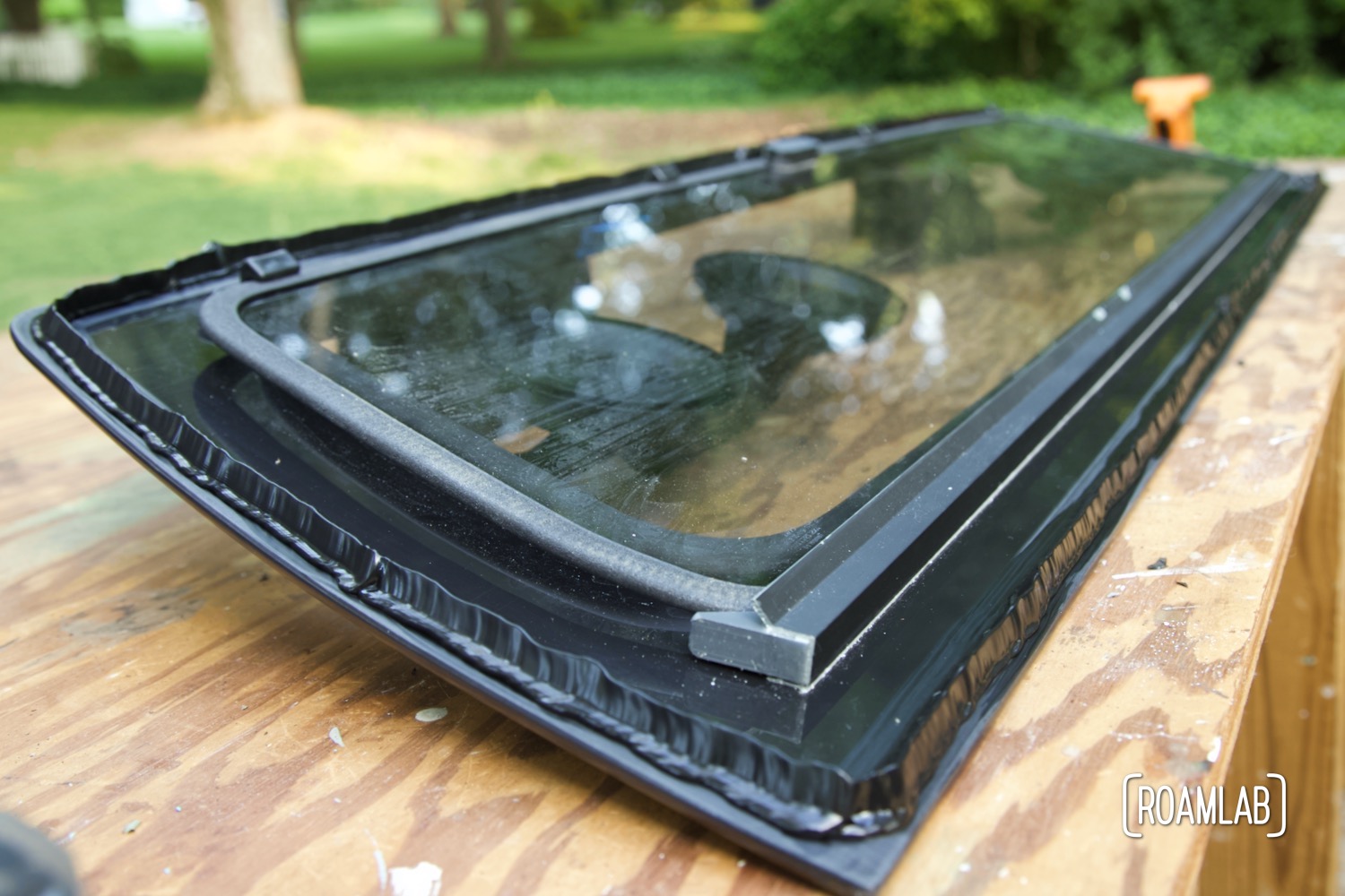Truck rear window set on a wood table with a bead of urethane along the edge.