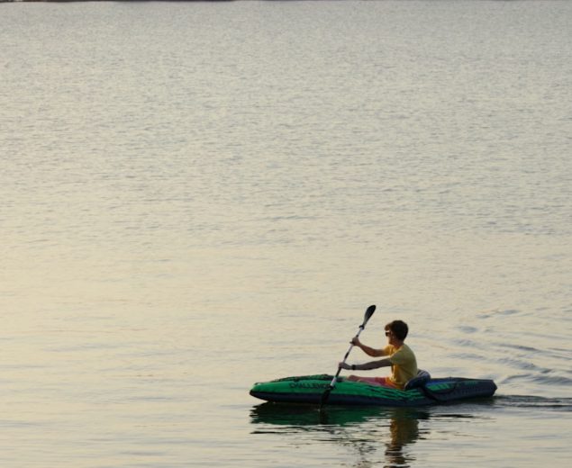 Man kayaking on a lake at sunset