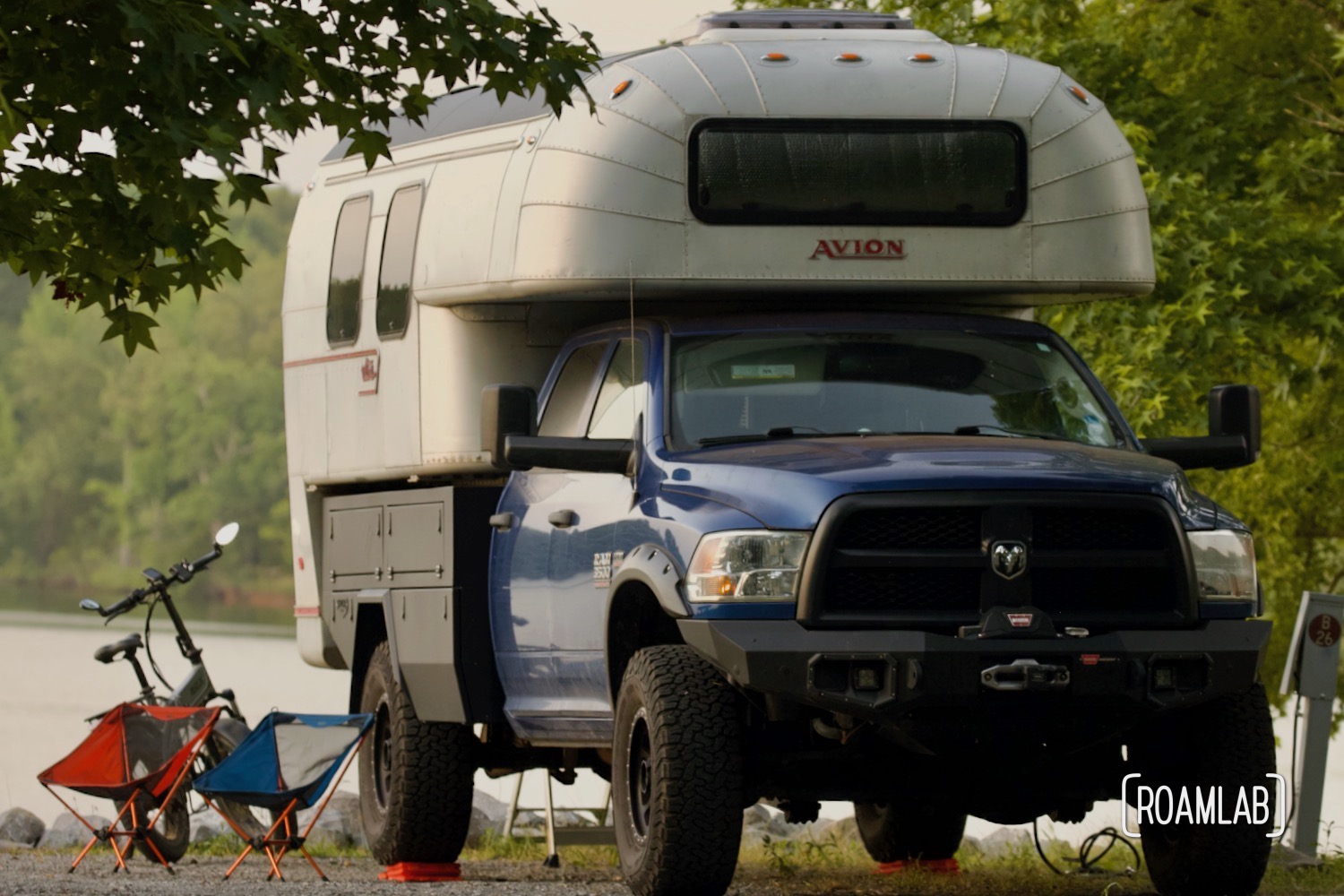 Avion C11 truck camper parked on the shore line under the shade of a tree.