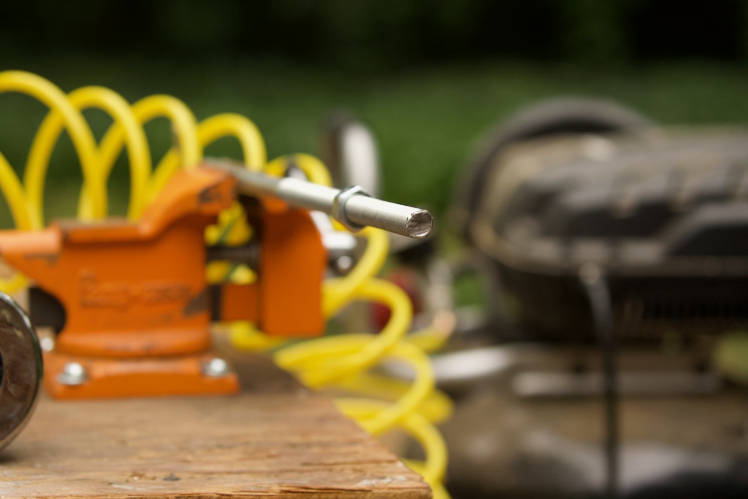 Closeup of threaded rod held in an orange workbench vice.