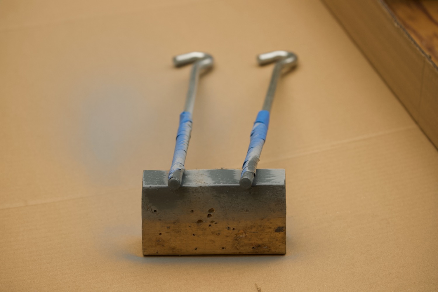 I-bolts resting on cardboard, covered in silver spray painti.