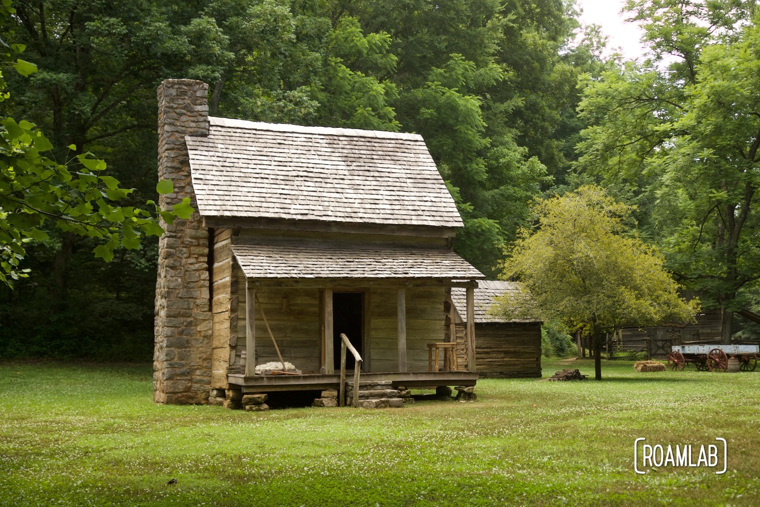 Single pen house sitting in a grassy clearing surrounded by woods.