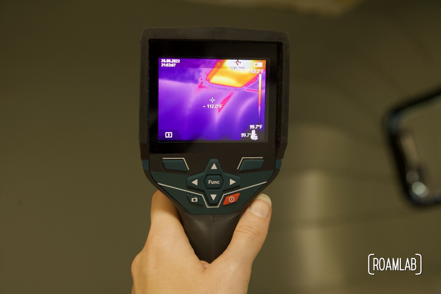 Hand holding thermal camera revealing hot spots in a truck camper cabover.