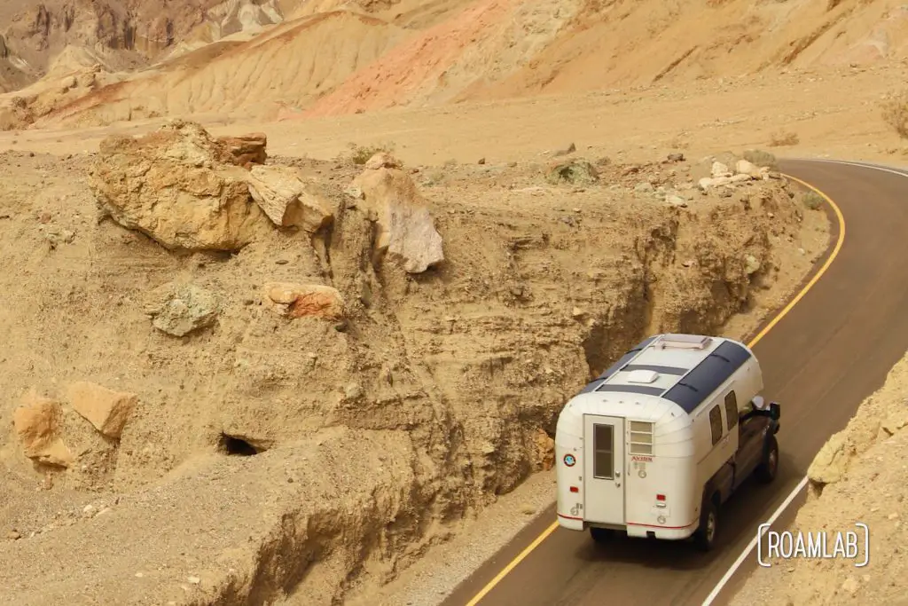 1970 Avion C11 truck camper with solar panels on a blue truck climbing up a desert road.
