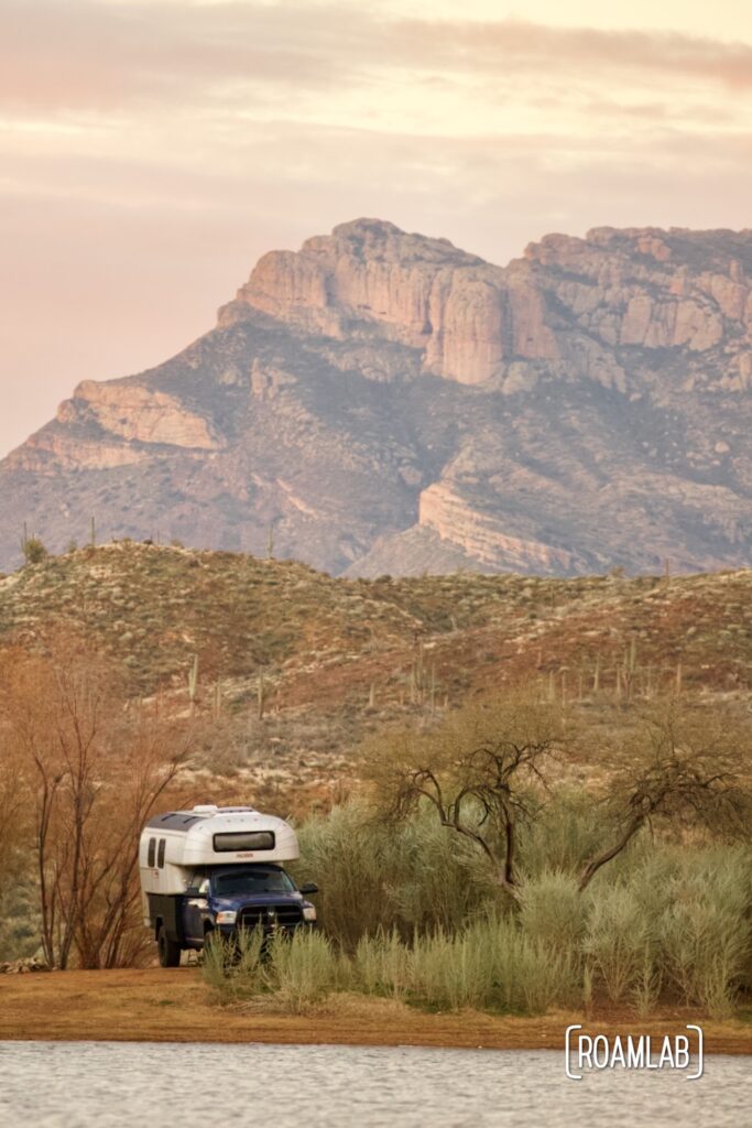 Avion C11 truck camper parked along the shoreline of Salt Lake with mountains in the background at sunrise.