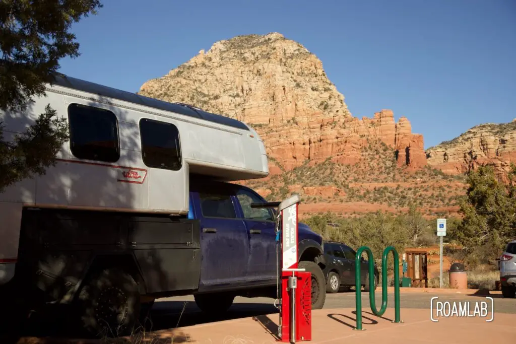 Avion C11 truck camper parked next to a bicycle repair station with red rock bluffs in the background.