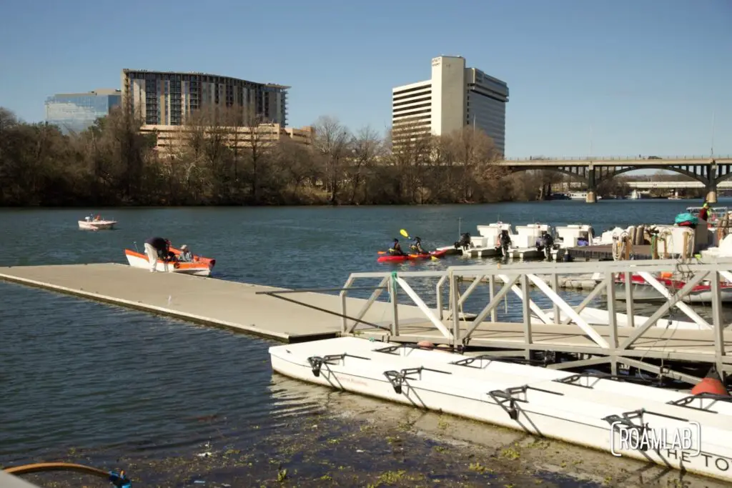Boaters loading into a small boat on a riverside dock.