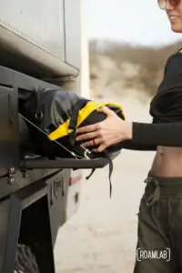 Woman placing a deflated yellow raft into a truck bed storage box.