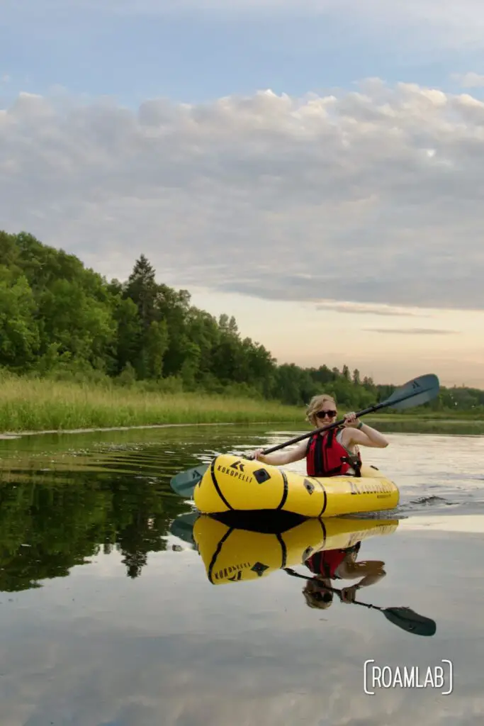 Woman paddling in a yellow raft at sunset.