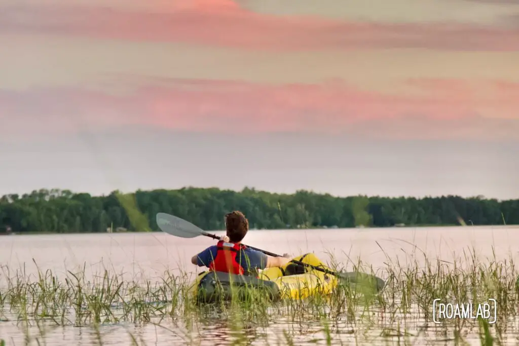 Man in a yellow raft glancing up at an expansive sunset.