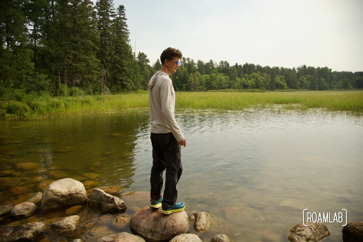 Man standing on a rock next to a lake.