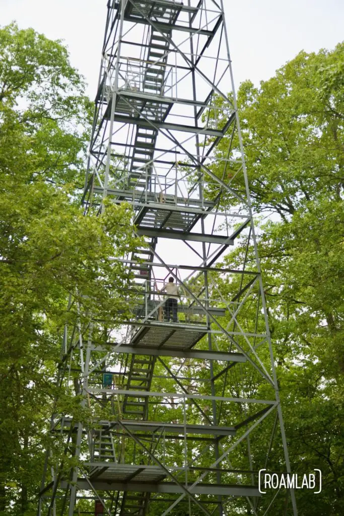 Man climbing a metal staircase up a fire tower.