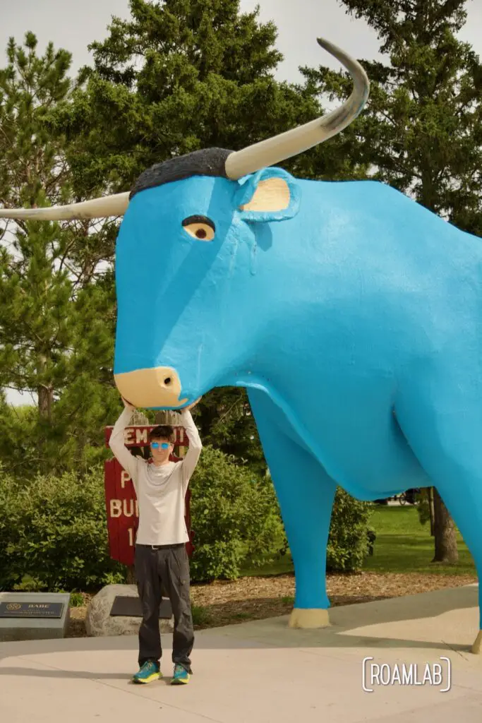 Man reaching up to scratch the nose of a statue of Babe the Blue Ox in Bemidji, Minnesota.