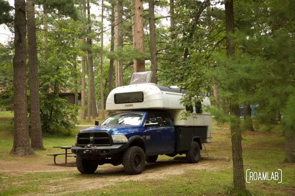 1970 Avion C11 truck camper parked among the woods of Lake Bemidji State Park in northern Minnesota.