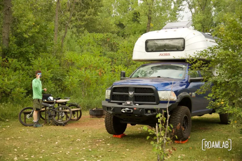 Man standing by mountain bikes and a 1970 Avion C11 truck camper.