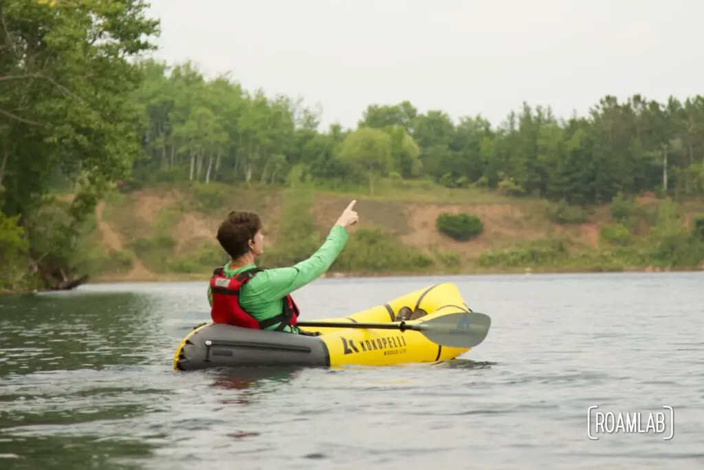 Man in a yellow raft on a lake pointing into the sky in Cuyuna Country State Recreation Area.