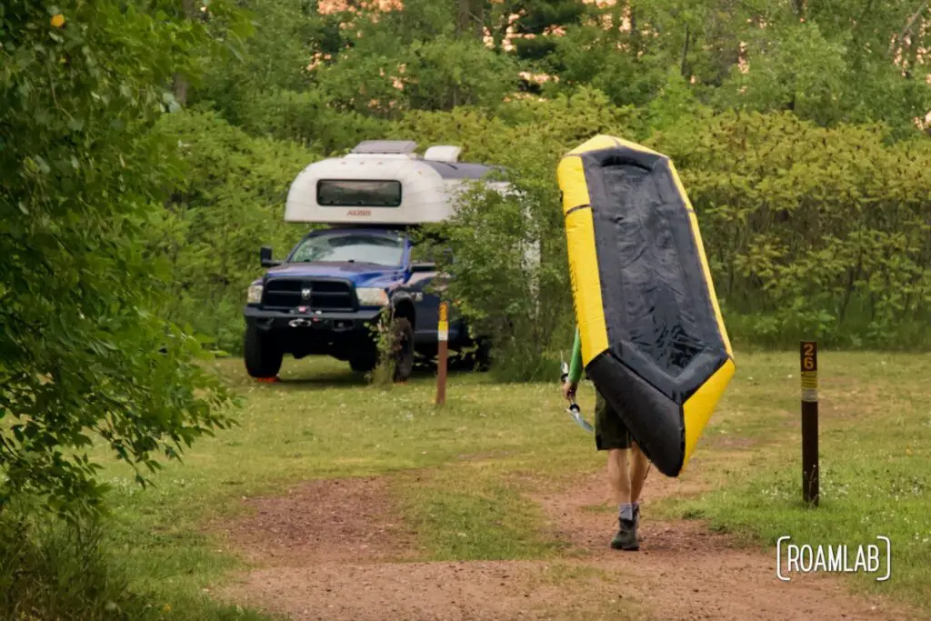 Man carrying a yellow raft to a 1970 Avion C11 truck camper.