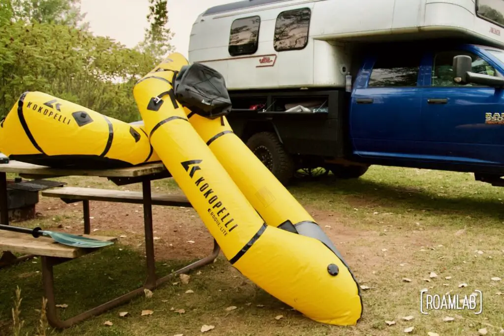 Yellow rafts propped against a picnic table with a truck camper in the background.