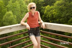 Smiling woman leaning up against a railing.