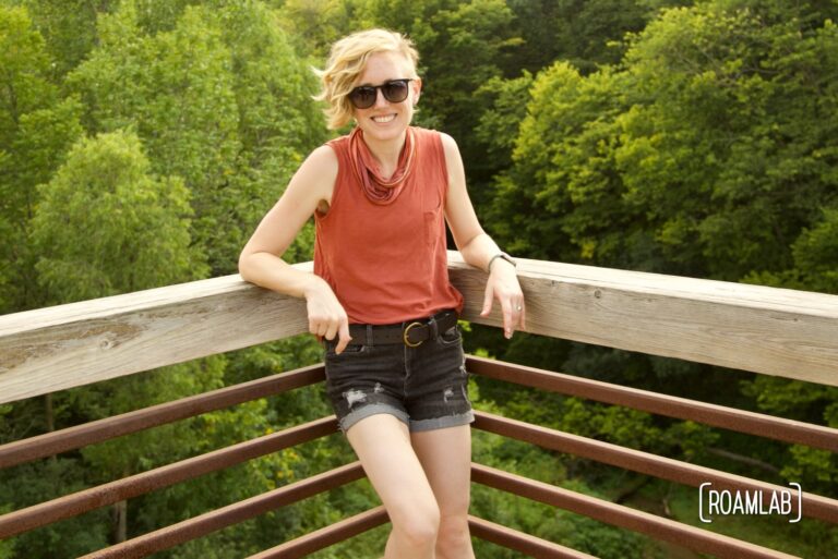 Smiling woman leaning up against a railing.