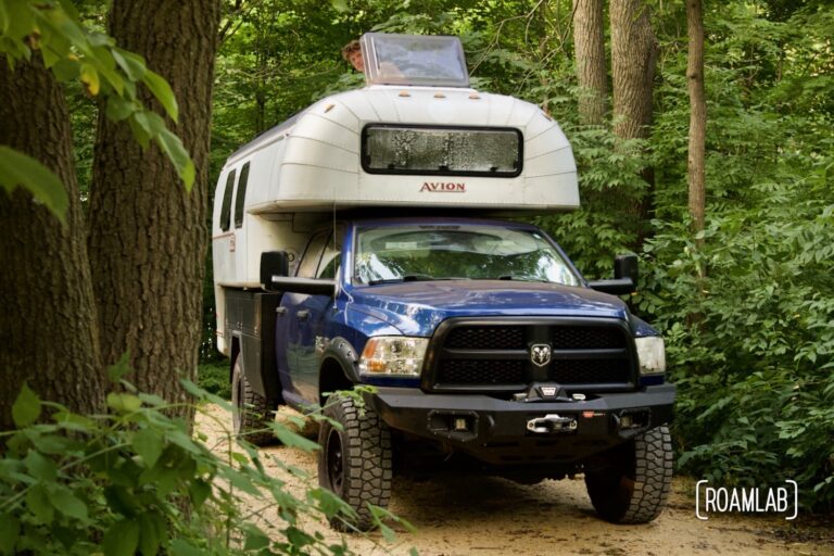 1970 Avion C11 truck camper parked in a forested campsite.